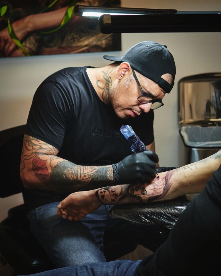 Tattoo artist working on arm tattoo.