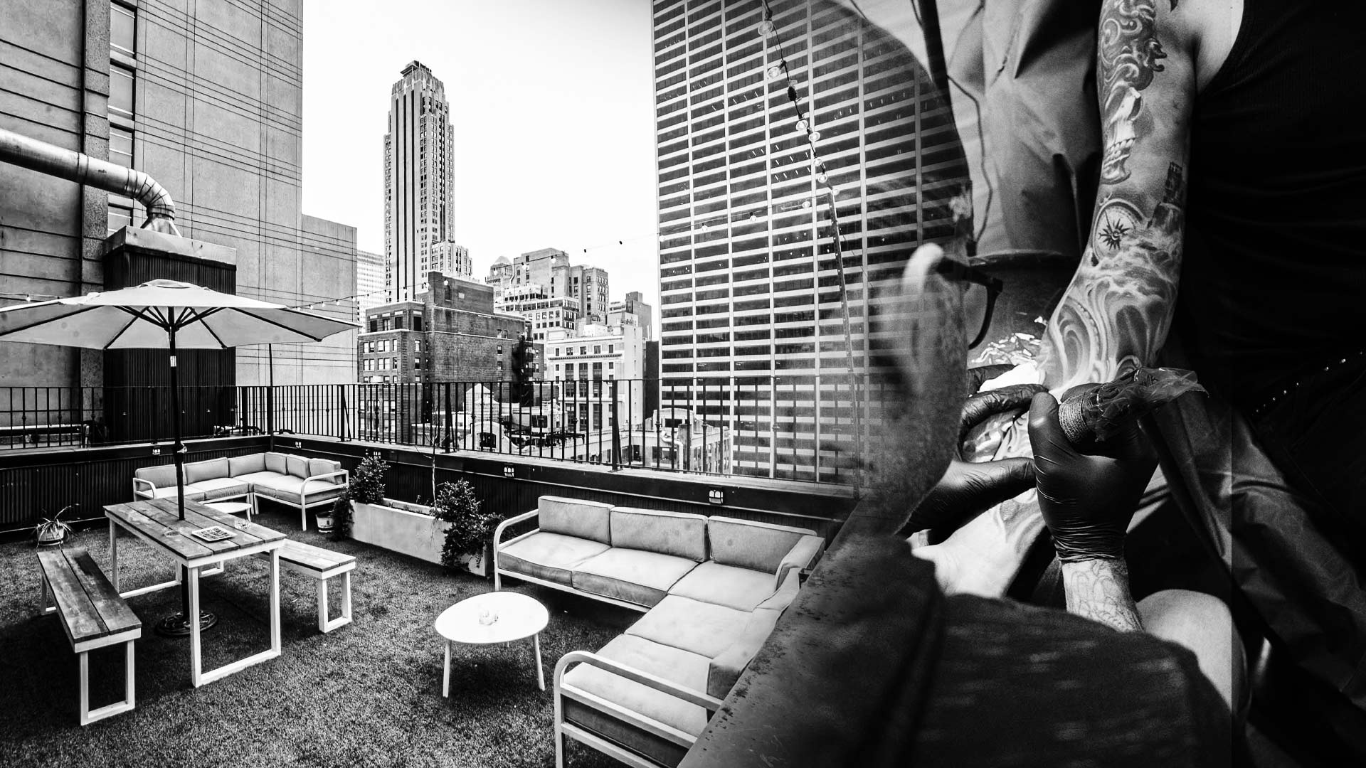 Rooftop tattoo studio in Midtown Manhattan with a tattoo artist working on a realism sleeve, representing Inknation Studio in New York City
