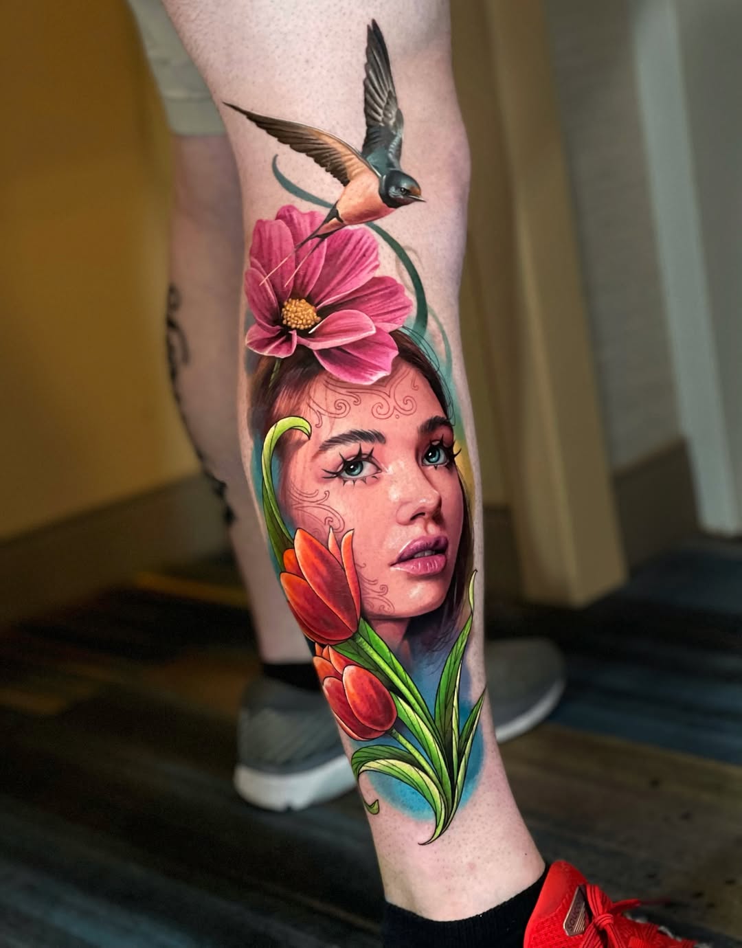 Color realism leg tattoo featuring a female portrait, flowers and bird created at a New York City tattoo studio specializing in high-end realism