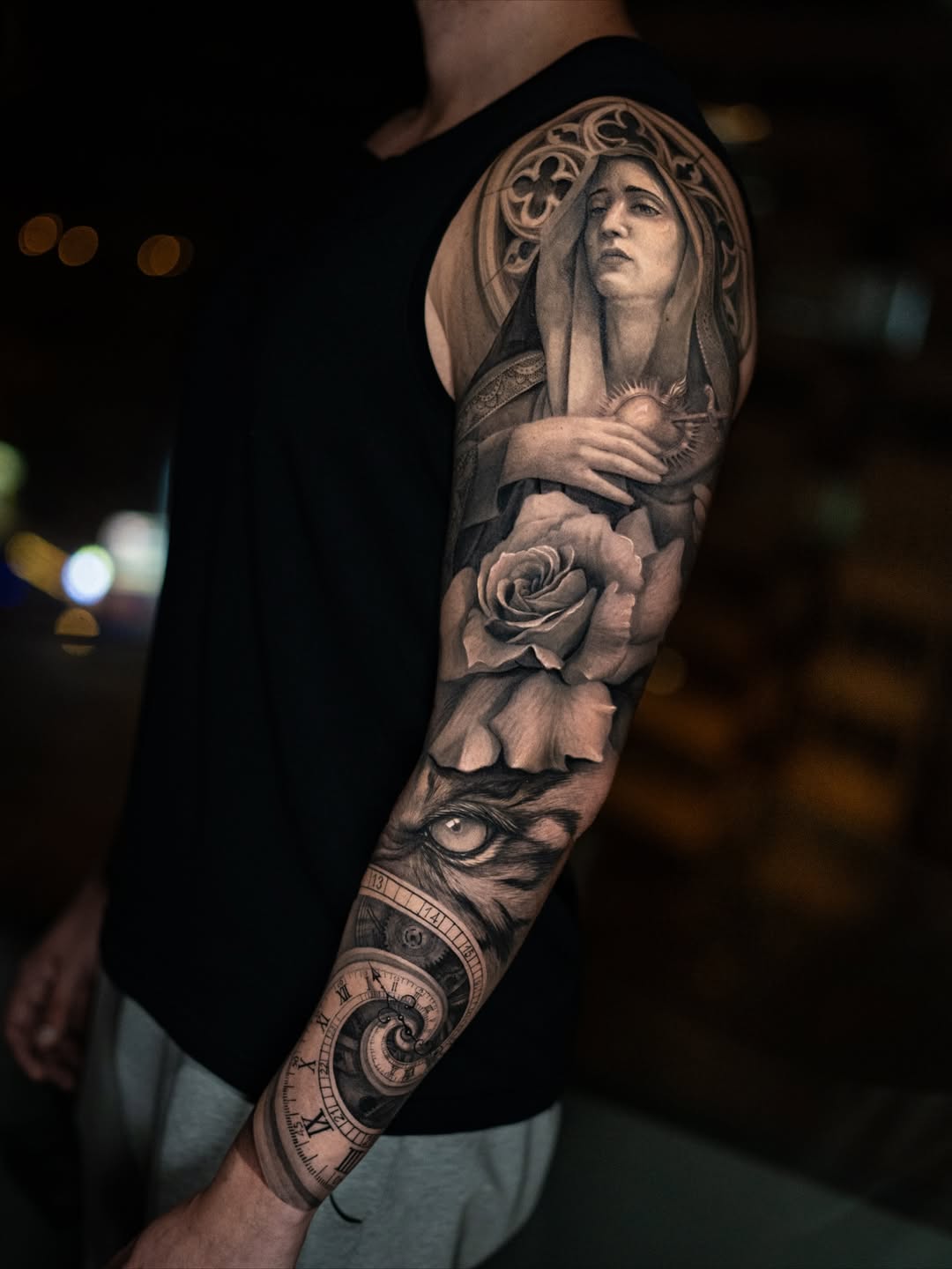 Black and grey realism full sleeve tattoo with religious portrait, rose, eye, and clock by Inknation Studio NYC