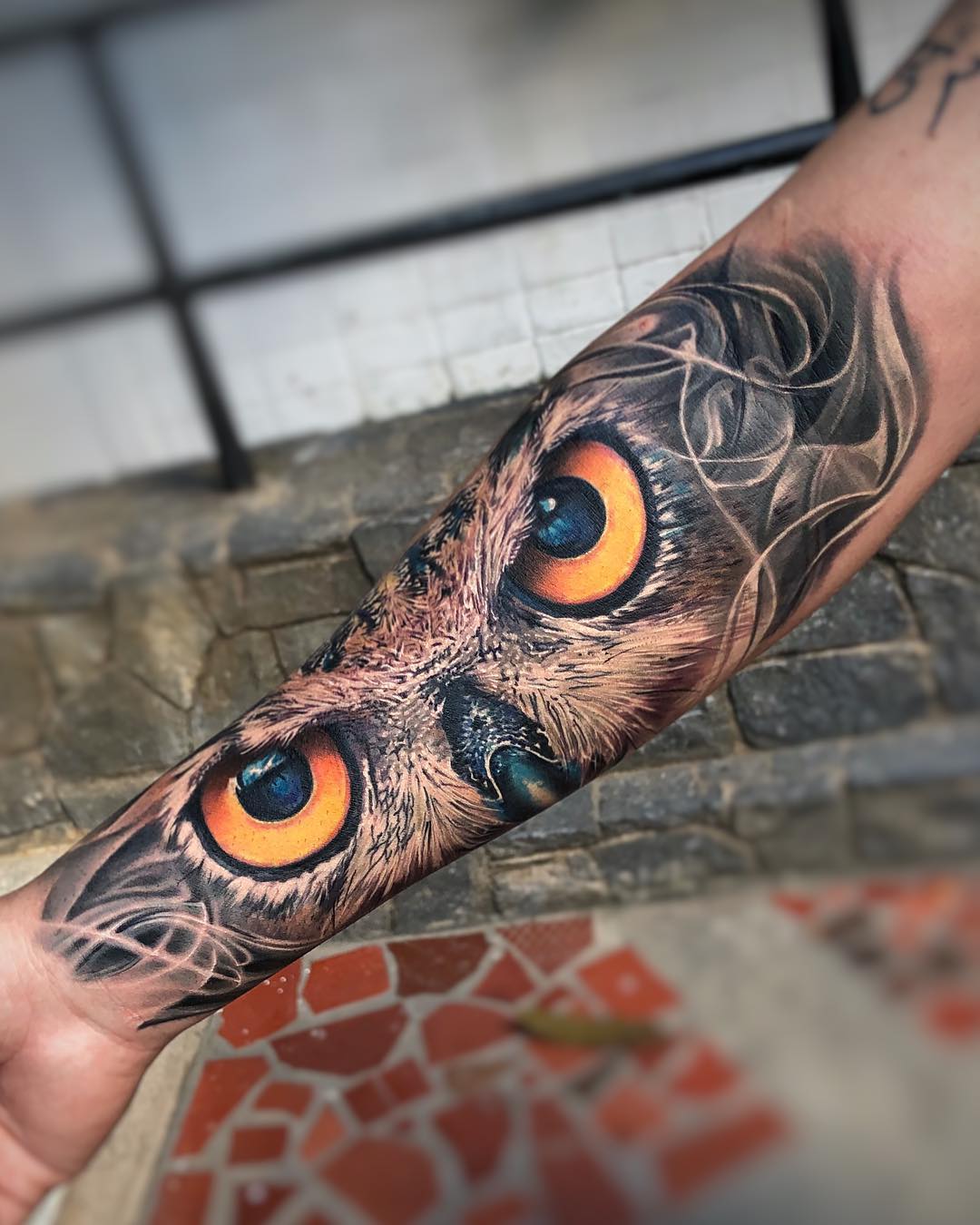 Realistic owl eyes tattoo on forearm in black and grey realism style, symbolizing wisdom and intuition
