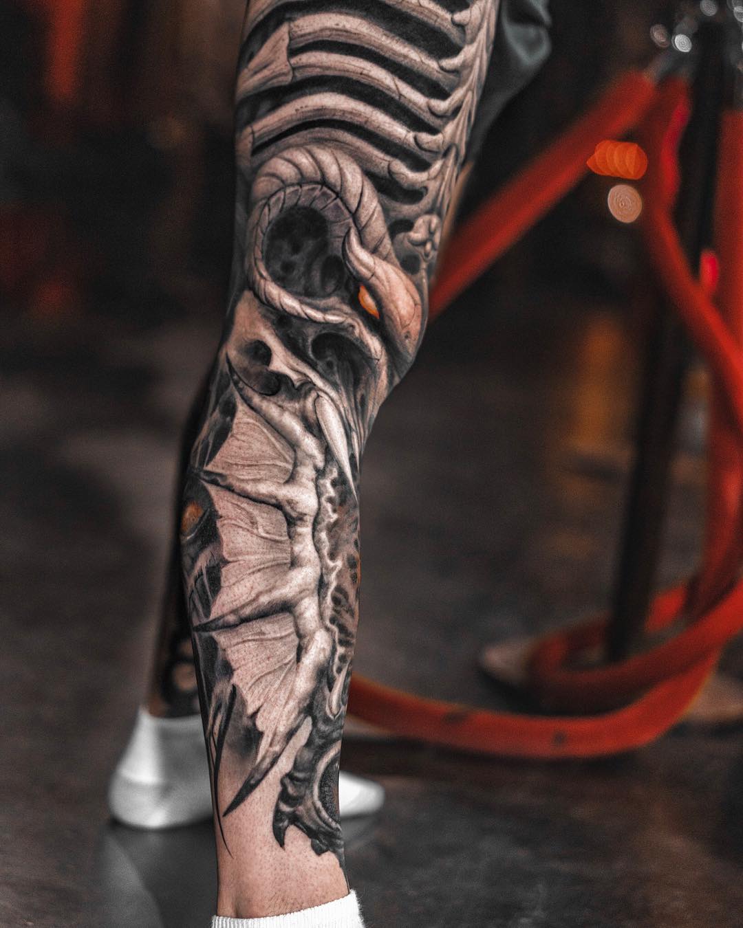Black and grey bio organic tattoo with skeletal ribs and tendrils on leg, surreal organic evolution, Inknation Studio