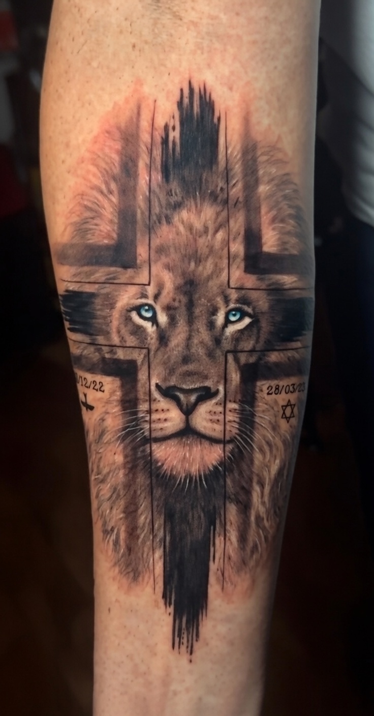 Black and grey lion with cross tattoo on forearm, symbolism of strength and faith, Inknation Studio NYC