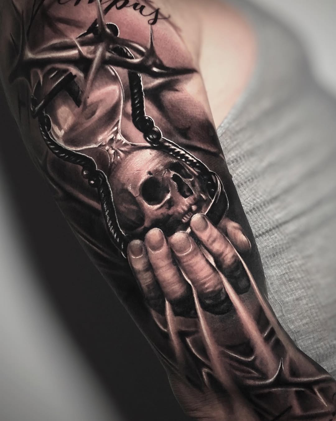 Black and grey realism hourglass tattoo with skull and thorns on forearm, memento mori symbolism, Inknation Studio