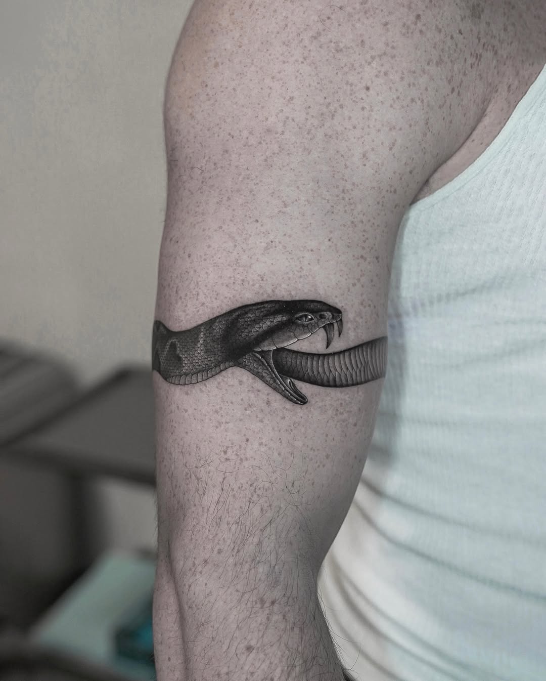 Black and grey realism striking snake head tattoo on upper arm, uroboro tattoo, Inknation Studio NYC