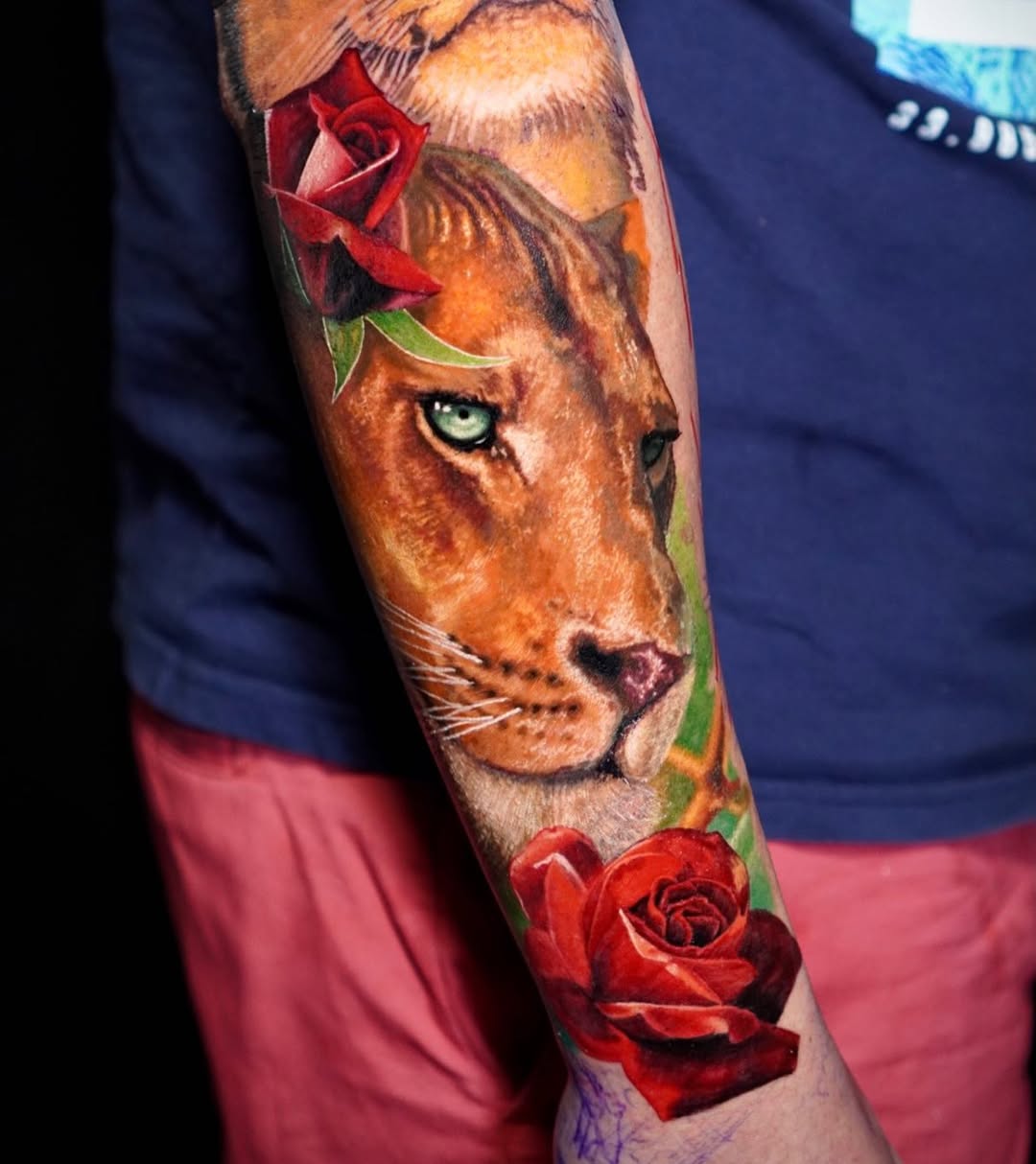 Color realism lioness tattoo on forearm with green eyes and red rose, strength symbolism, Inknation Studio NYC