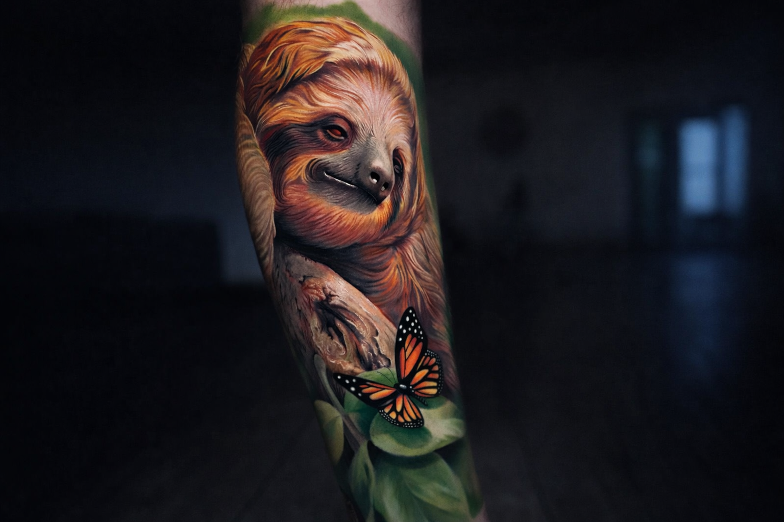 Color realism sloth forearm tattoo with orange butterfly, calm symbolism, Inknation Studio NYC | realistic animal tattoos