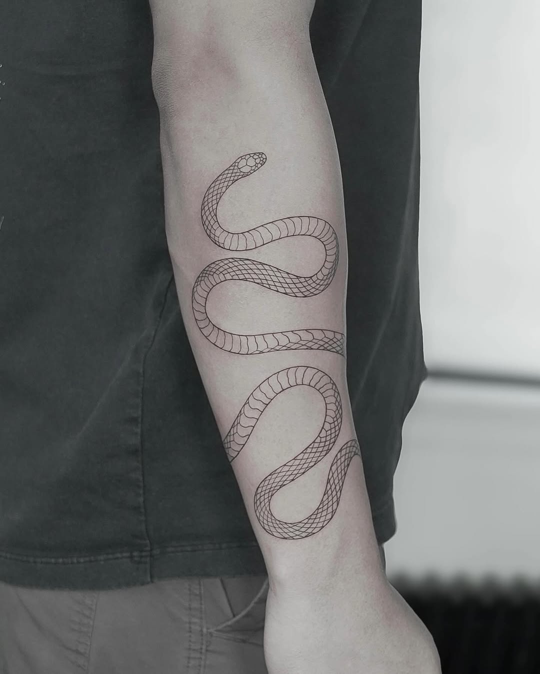 Minimalist fine line snake tattoo on forearm in black and grey, Inknation Studio NYC