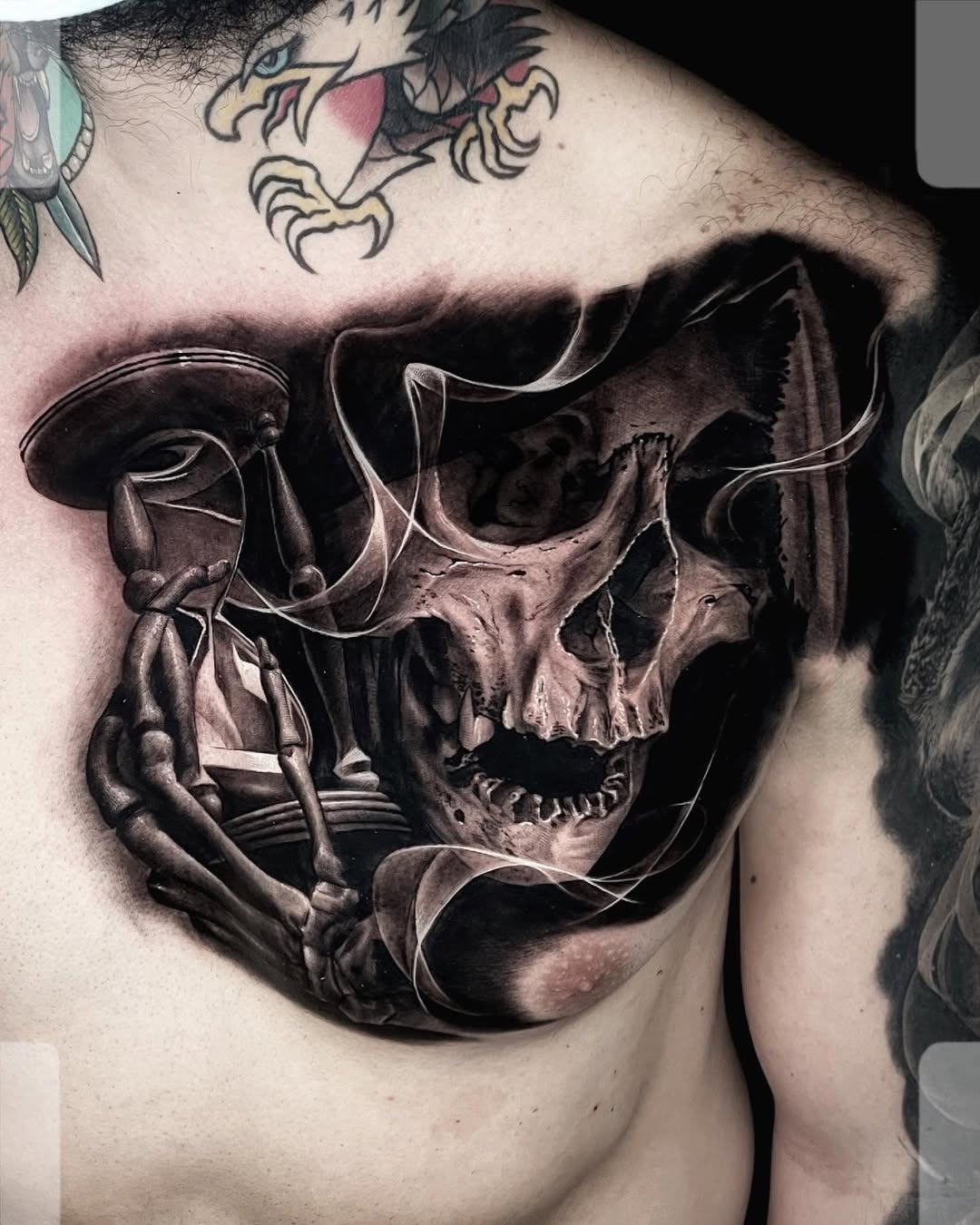 Black and grey realism hourglass tattoo with skeleton hands and thorns on chest or arm, memento mori, Inknation Studio