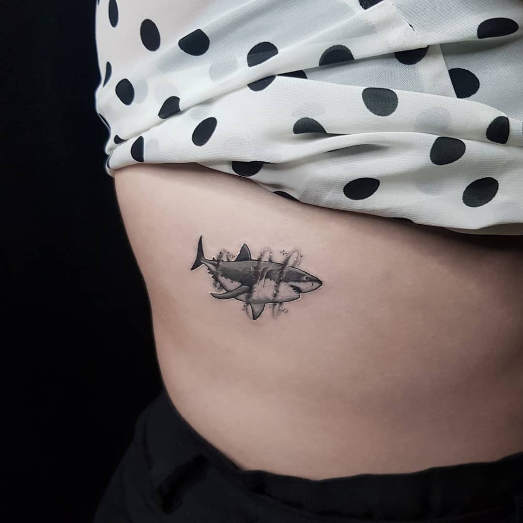 Small black and grey great white shark tattoo on ribcage with water splash, Inknation Studio